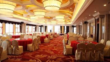 Un salón de banquetes con mesas redondas, sillas y candelabros.