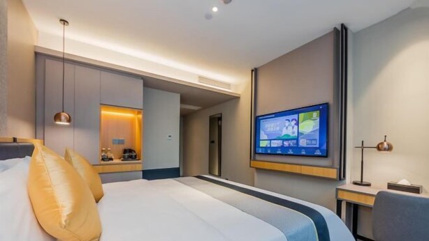 A modern hotel room with a large bed, a flat-screen TV mounted on the wall, and a desk with a lamp. - Jiatai Chain Business Hotel (Zhuanghe High-speed Railway Station) (Zhuanghe)