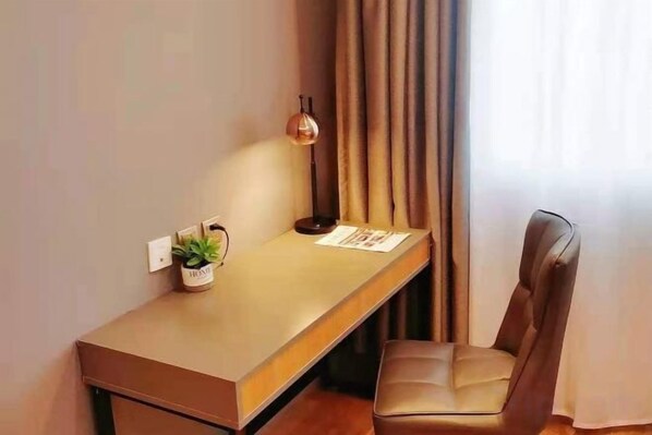 A modern room with a desk, chair, lamp, and a small plant.