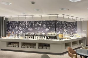 A breakfast bar with a variety of food items and a wall with doodle patterns. - Jiatai Chain Business Hotel (Zhuanghe High-speed Railway Station) (Zhuanghe)