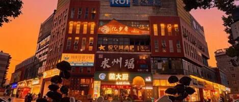 A multi-story building with various commercial establishments on the ground floor, including a restaurant and a store with a prominent sign.