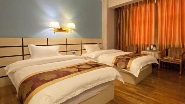 Una habitación de hotel con dos camas, una mesita de noche, una lámpara y una silla.