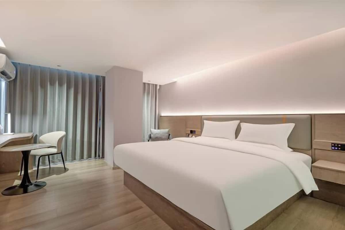 A modern hotel room with a large bed, a desk, and a chair.