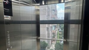 Interior de un ascensor con paredes metálicas y una ventana de vidrio.