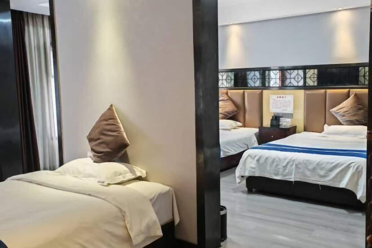A hotel room with two beds, a large mirror, and a view of the adjacent room.