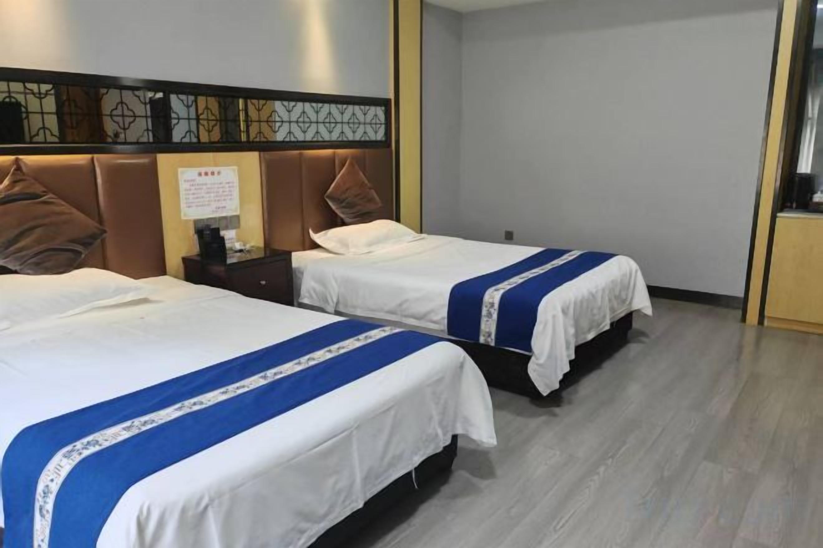 A hotel room with two beds, a nightstand, and a decorative headboard.