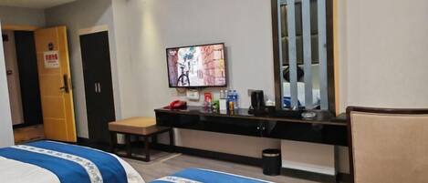 A hotel room with two beds, a desk, a chair, a TV, and a mirror.