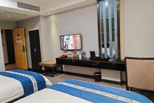Habitación de hotel con dos camas, un escritorio, una silla, un televisor y un espejo.