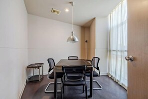 A conference room with a rectangular table, six chairs, a hanging light fixture, and a window with curtains. - City Garden Hotel Chain (Chizhou Vocational College Xiushanmen Millennium Ancient City Building ) (Chizhou)