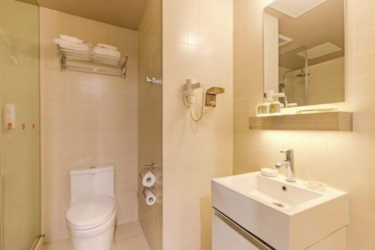 A modern bathroom with a toilet, a sink, a mirror, and a towel rack.