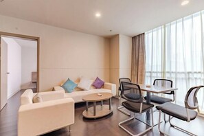 A modern hotel room with a sofa, a round coffee table, and a dining table with chairs. - City Garden Hotel Chain (Chizhou Vocational College Xiushanmen Millennium Ancient City Building ) (Chizhou)