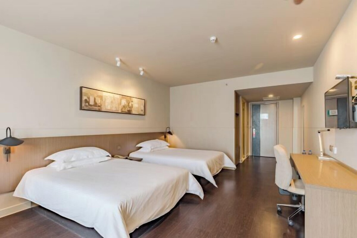 A hotel room with two beds, a desk, and a chair.