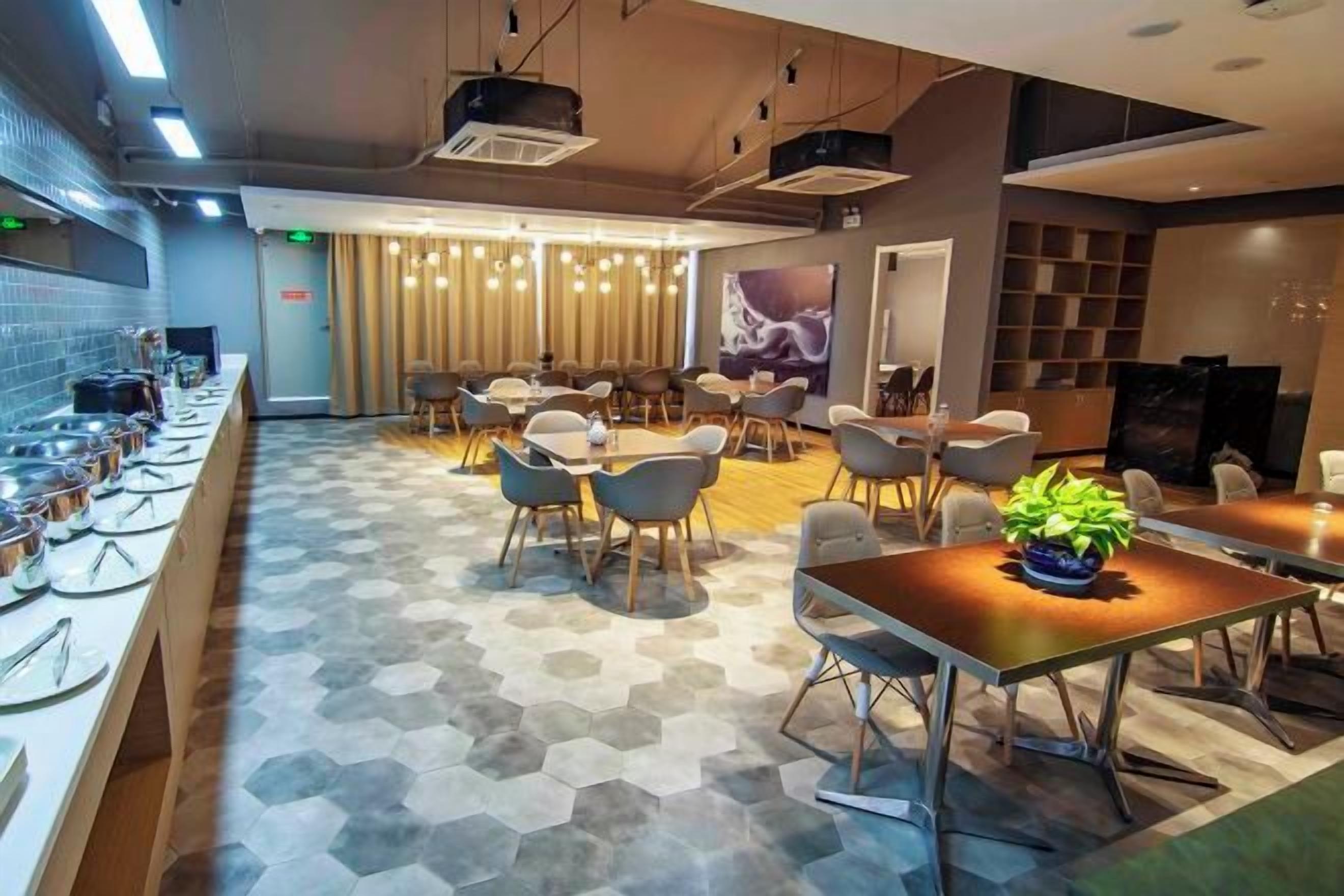 A modern hotel lobby with a long reception desk, seating area, and a television screen.