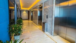 A modern hallway with marble flooring, potted plants, and elevators. - Shubohao Hotel (Hangzhou)