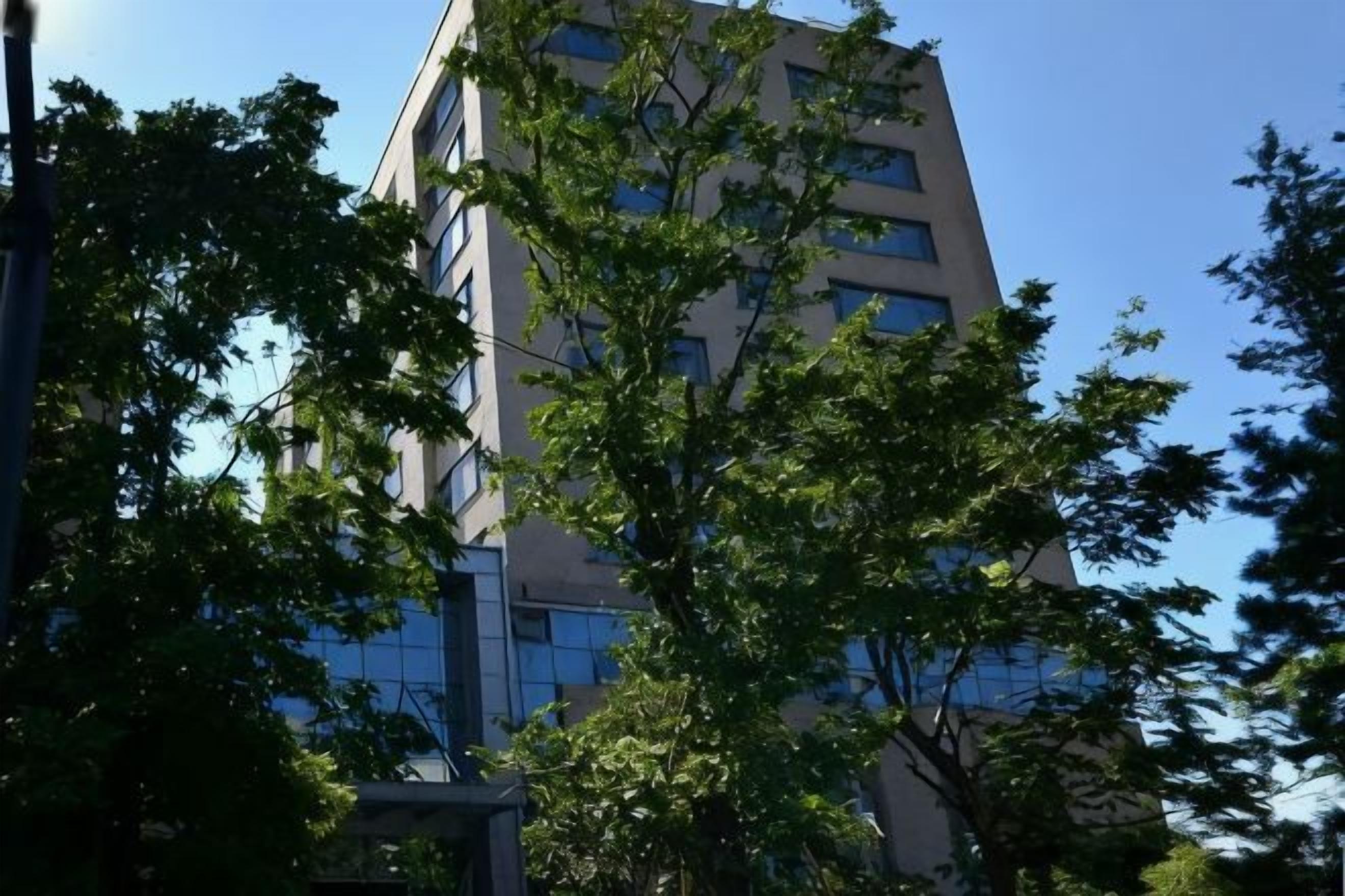 Um edifício moderno de vários andares, cercado por árvores.