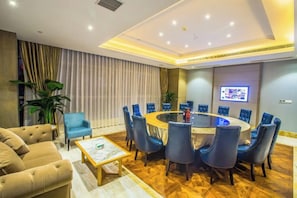 Une salle de conférence moderne avec une table ronde, des chaises bleues et un écran de télévision.