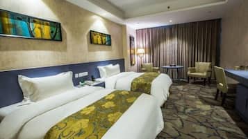 A hotel room with two beds, a desk, a chair, and artwork on the walls.
