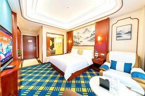 Une chambre d’hôtel avec un grand lit, un bureau, une télévision et un tableau au mur.