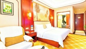 A hotel room with a bed, a sofa, a nightstand, and a painting on the wall.