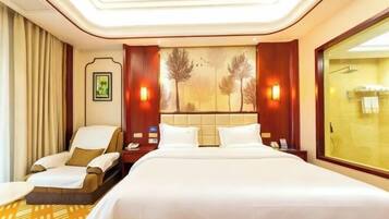 A hotel room with a large bed, a chair, a nightstand, and a window.