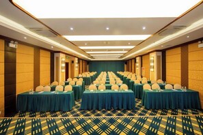 A conference room with rows of tables, each with a round table and chairs, and a carpeted floor. - Huang Jia Hotel Mangshi Square Mangshi Jewelry Town (Mangshi)
