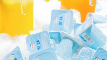 A collection of blue containers with Chinese characters, possibly dairy products, on a surface with a yellow liquid in the background.