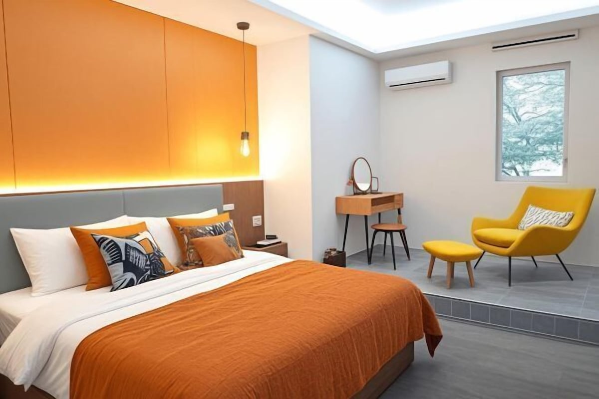 A modern bedroom with a bed, a desk, a chair, and a window.