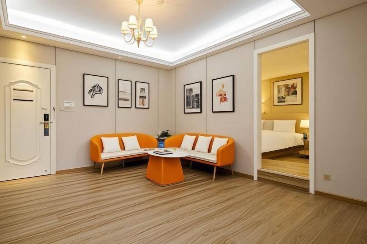 A hotel room with a wooden floor, a sofa, a coffee table, and framed pictures on the wall.