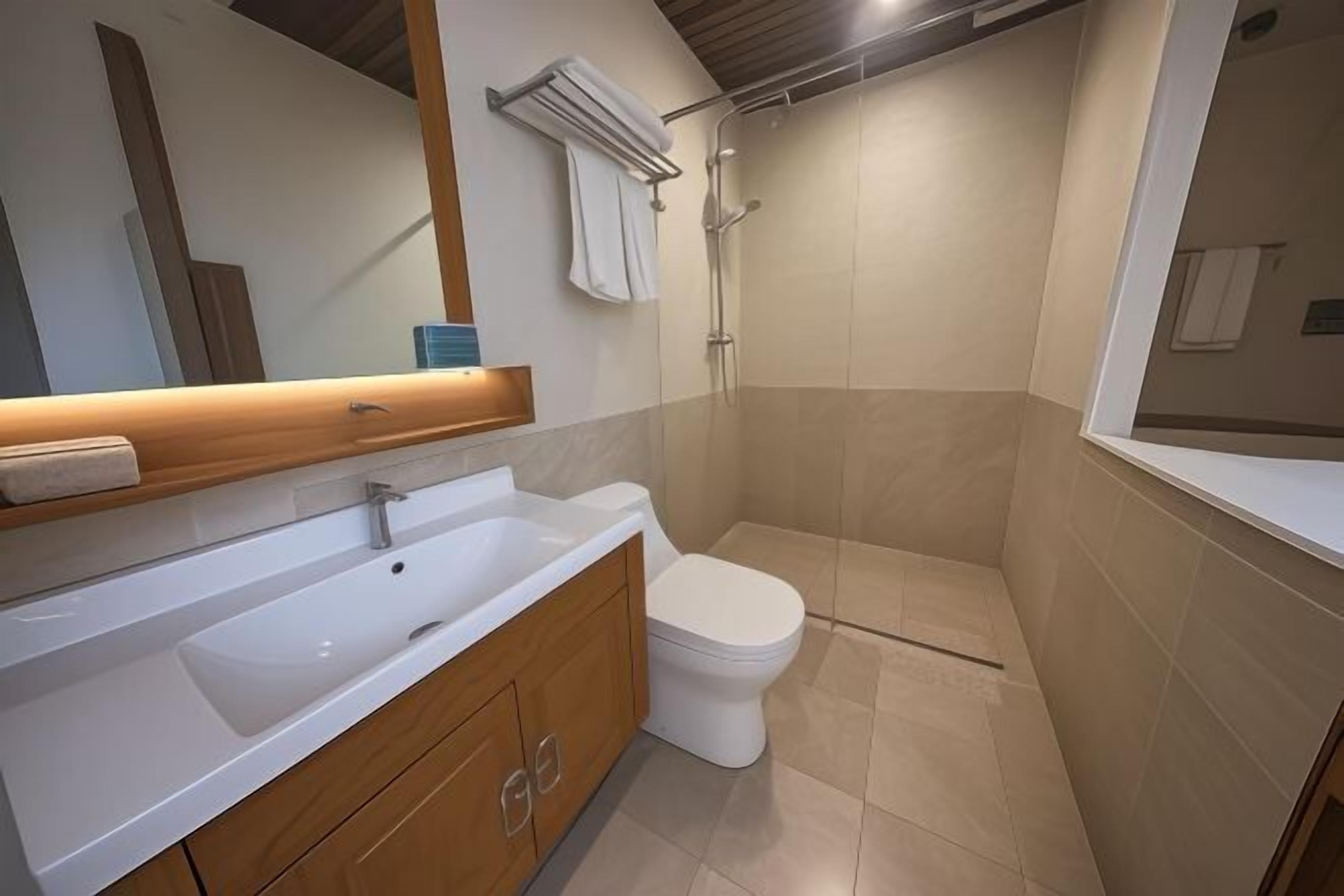 Ein modernes Badezimmer mit einem weißen Waschbecken, einem Holz-Badmöbel und einer Dusche.