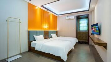 Quarto de hotel moderno com duas camas, televisão e claraboia.