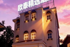 A multi-story building with illuminated windows and a sign at the top. - Shantou Outai Select Hotel (Shantou)