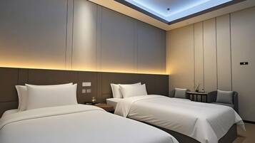 A hotel room with two beds, a small table, and a chair.
