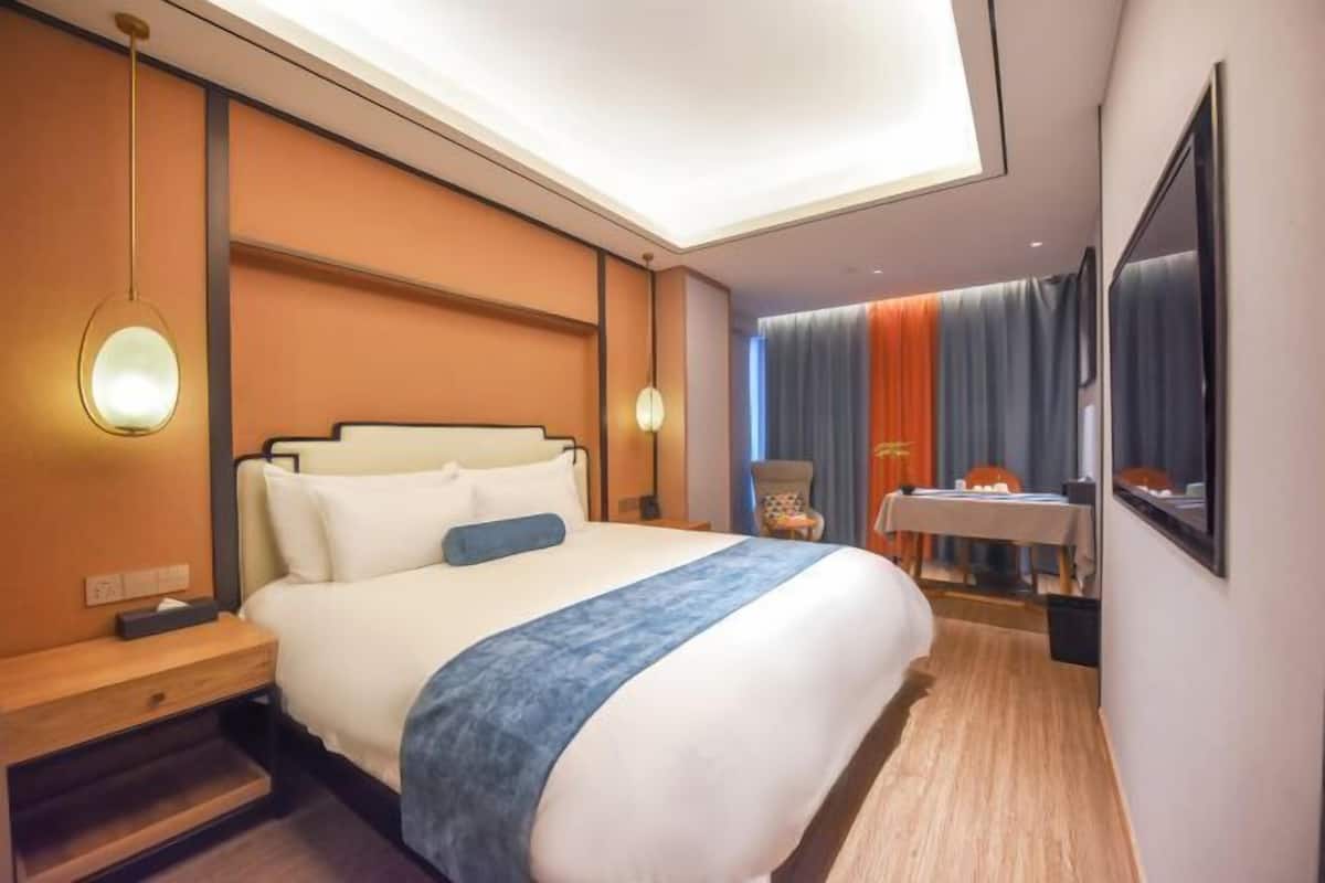 A hotel room with a large bed, bedside tables, a desk, and a chair.