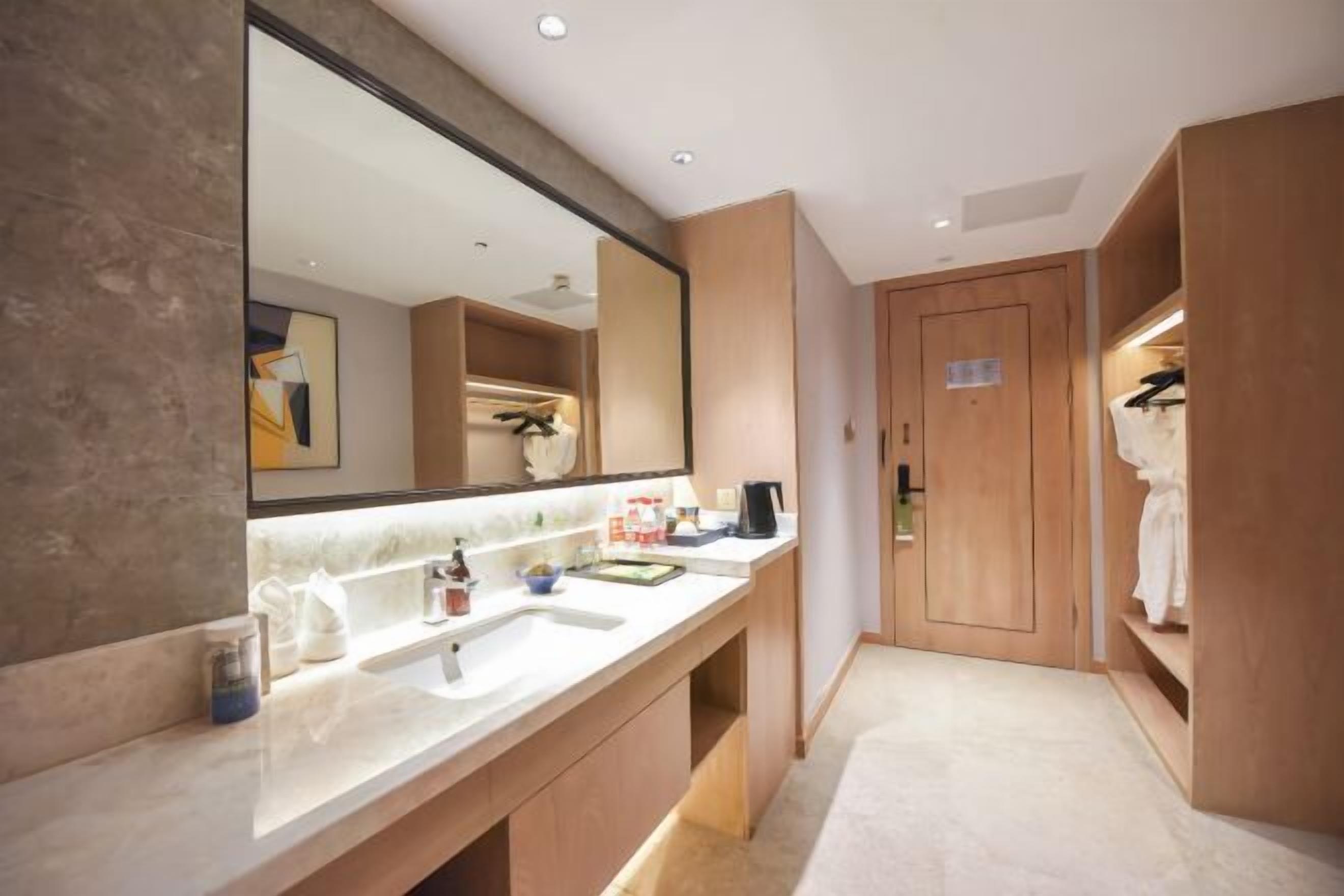 Un baño moderno con un espejo grande, dos lavamanos y armarios de madera.