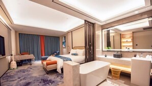 Ein modernes Hotelzimmer mit Bett, Schreibtisch, Bad und einem großen Spiegel.