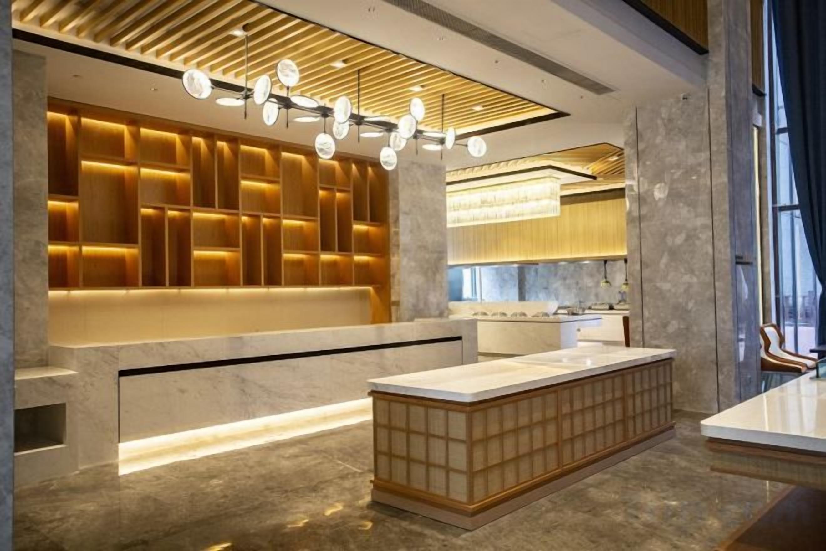 Cozinha moderna com bancada de mármore, prateleiras embutidas e iluminação pendente.