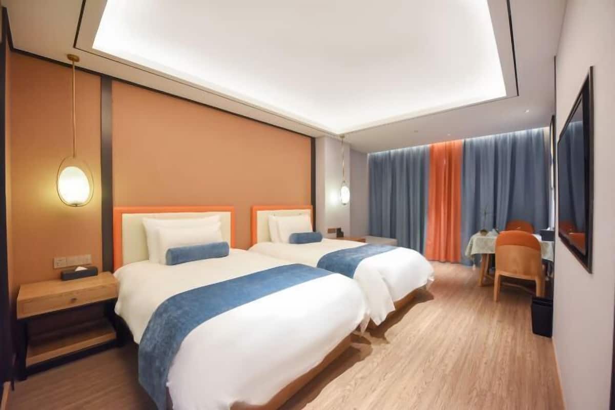 A hotel room with two beds, a desk, and a chair.