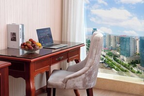 A modern office with a laptop on a glass table, a plush chair, and a cityscape view through a large window.