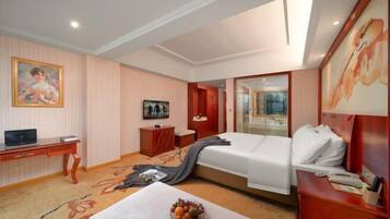 A hotel room with a bed, a desk, a chair, a TV, and a painting on the wall.