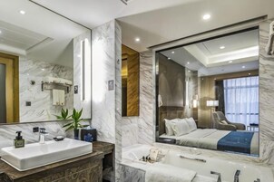 Un baño moderno con un espejo grande, un lavamanos, una bañera y una ducha.