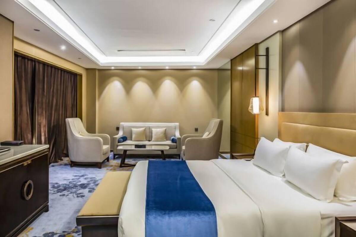 A hotel room with a large bed, two armchairs, a sofa, and a desk.
