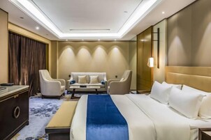 Una habitación de hotel con una cama grande, dos sillones, un sofá y un escritorio.