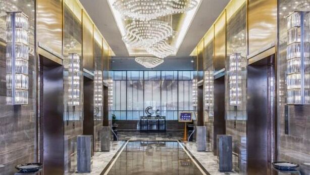 A modern hotel lobby with a reflective marble floor, a large chandelier, and a reception desk. - Shangqiu Xinhua Jianguo Hotel (Shangqiu)