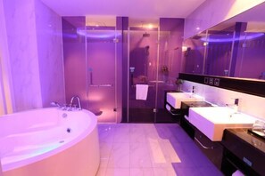 Ein modernes Badezimmer mit einer großen Badewanne, zwei Waschbecken und einer Duschkabine aus Glas.