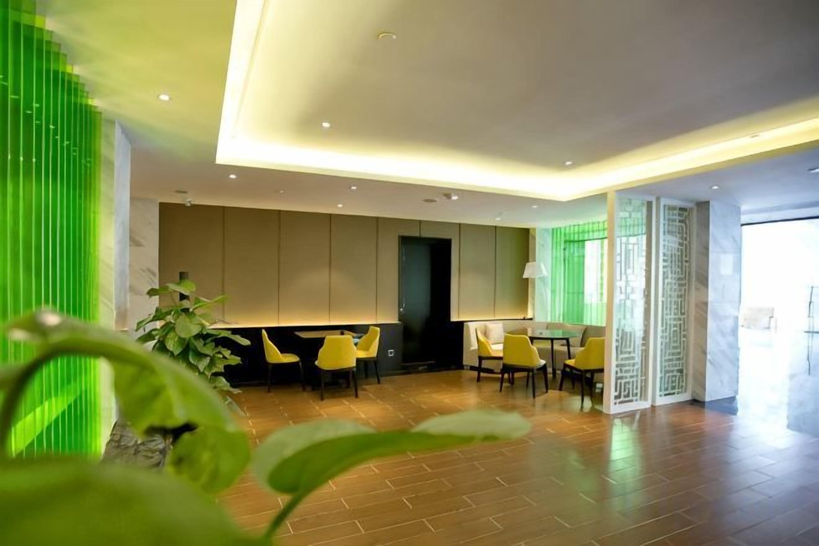 Un hall d’hôtel moderne avec un comptoir d’accueil, un espace salon et une grande fenêtre.