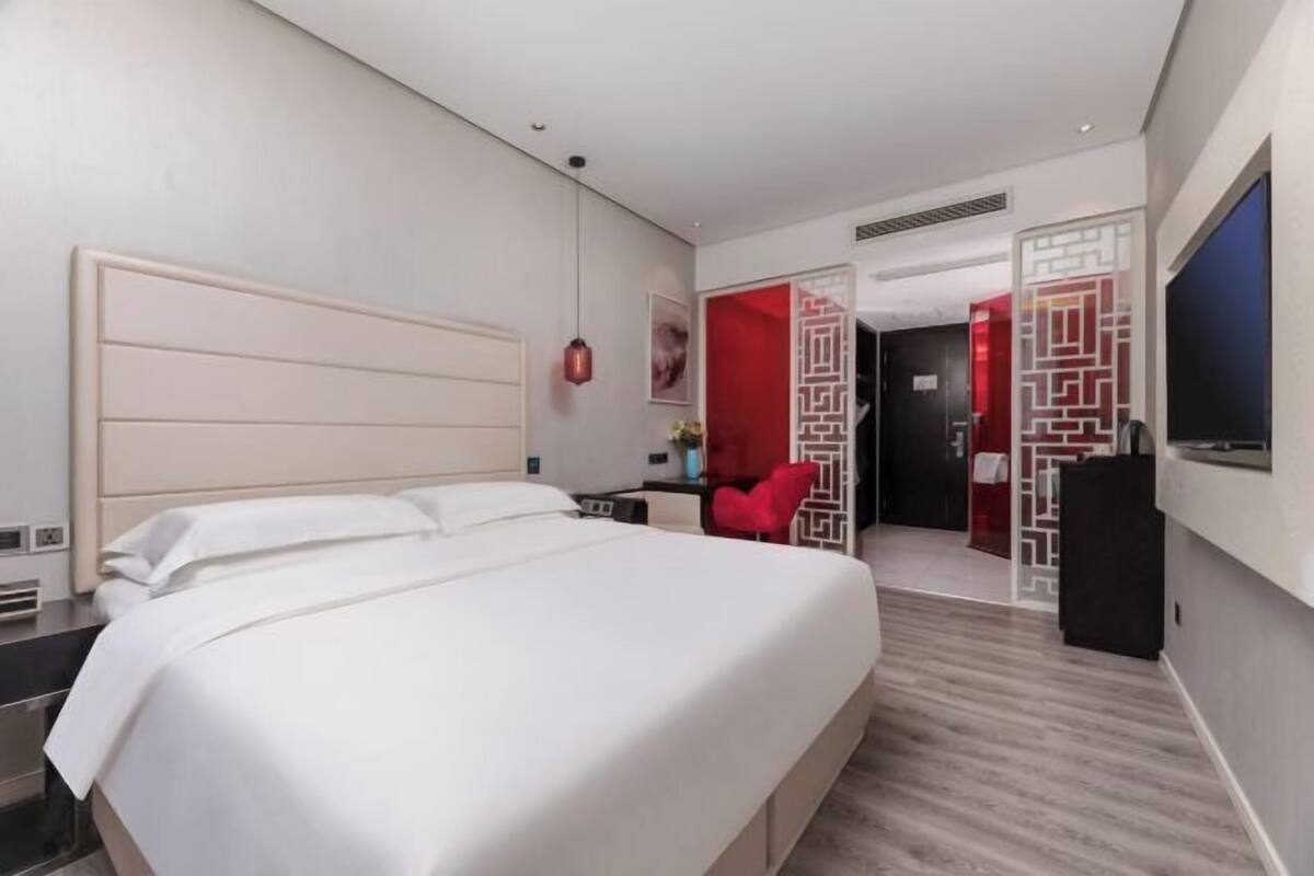 Una habitación de hotel con una cama grande, un escritorio, una silla, un televisor y un panel decorativo en la pared.