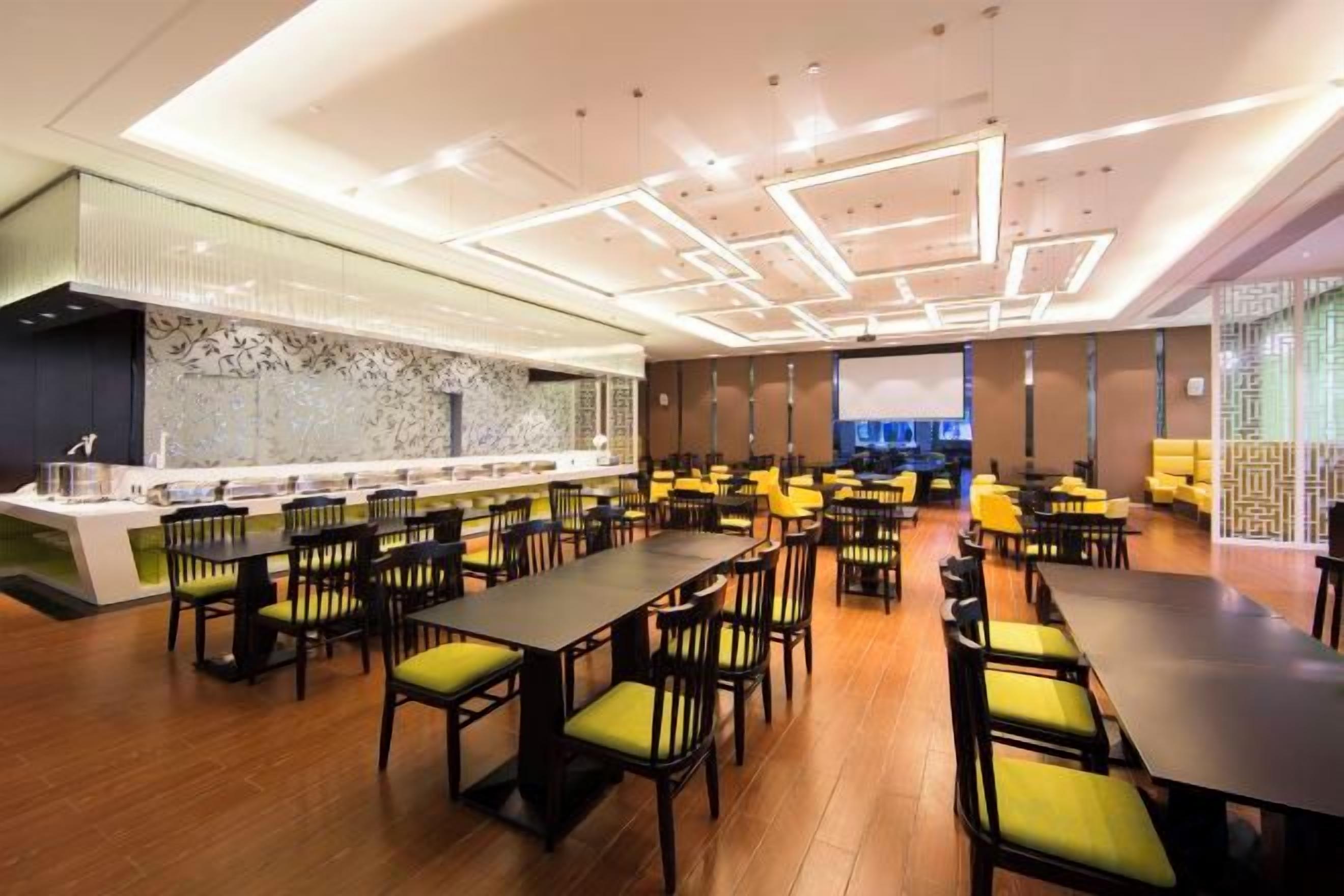 A modern dining area with multiple tables and chairs, a bar counter, and a decorative wall.