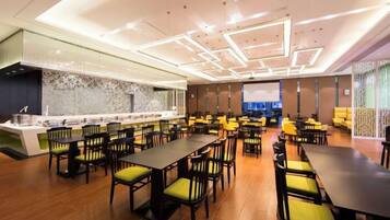 A modern dining area with multiple tables and chairs, a bar counter, and a decorative wall.