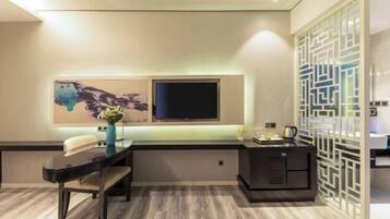 A modern living room with a flat-screen TV, a dining table, and a decorative wall piece.