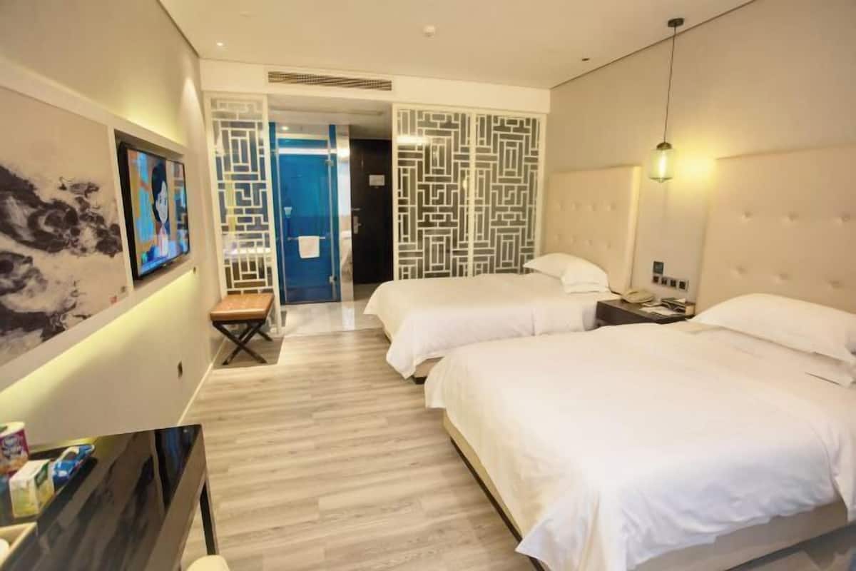 Una habitación de hotel con dos camas, televisión, escritorio y un adorno en la pared.